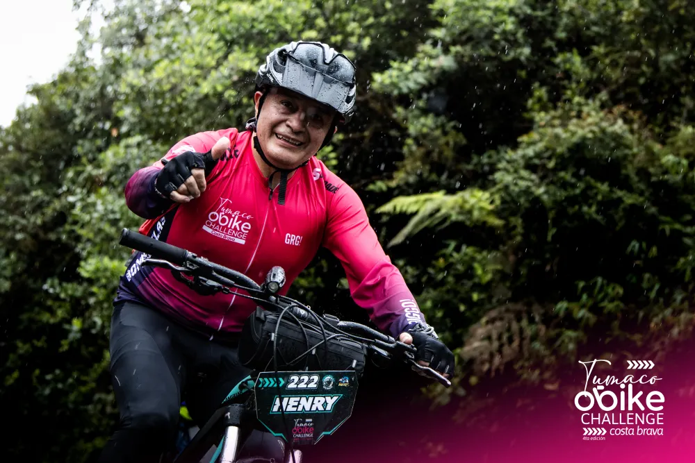 Ciclista con el jersey oficial rosado sonriendo en el bosque de niebla