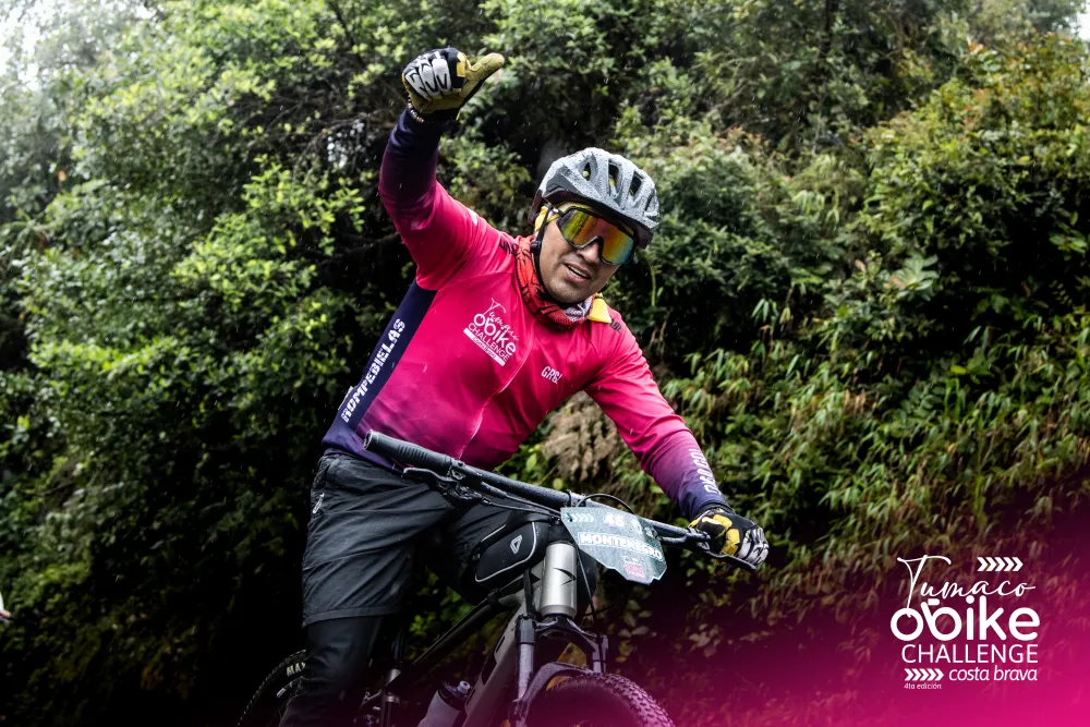 Ciclista con jersey oficial rosado celebrando con el brazo en alto