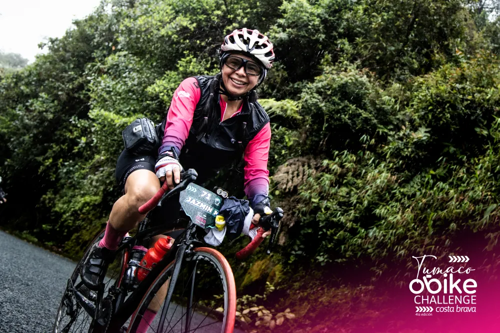 Ciclista con jersey oficial rosado sonriendo entre la vegetación